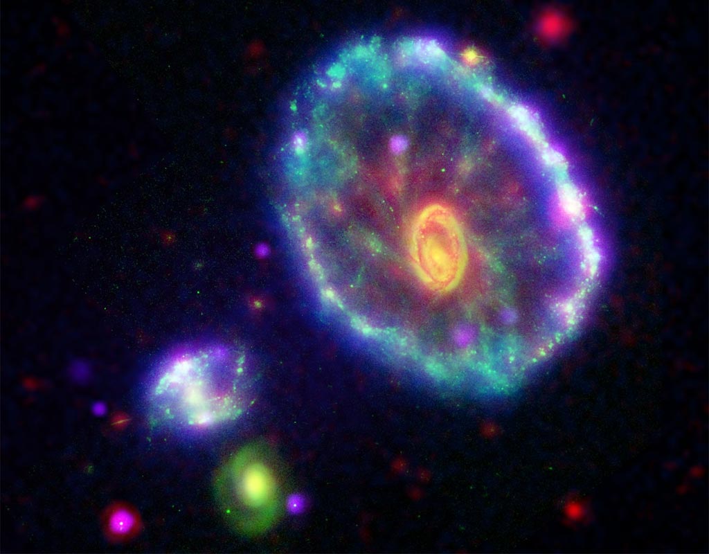 La imagen compuesta en falso color muestra la Galaxia Rueda de Carroc omo lo ve el Galaxy Evolution Explorer^s Far Ultraviolet detector (blue); el Hubble Space Telescope^s Wide Field and Planetary Camera-2 en banda B en luz visible (verde); el Spitzer Space Telescope^s Infrared Array Camera (IRAC) de 8 micrones (rojo); y el Chandra X-ray Observatory^s Advanced CCD Imaging Spectrometer-S array instrument (p�rpura)