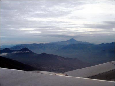 Silueta del volc�n Cotacachi desdee la ventanilla del avi�n al amanecer, hacia la izquierda en primer plano el volc�n Pululahua