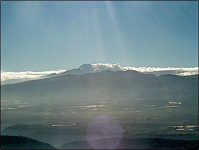 Vista del Cayambe desde Quito en la madrugada, apenas visible tras las nubes, el volc�n Cayambe es fuente de agua para la creciente agroindustria y las exportaciones de flores que se han desarrollado en sus cercan�as. En primer plano en silueta el volc�n extinto Pambamarca.
