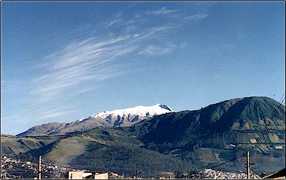 Vista del volc�n Guagua Pichincha desde el sur de la ciudad de Quito. El volc�n se presenta nevado como es com�n en invierno. En primer plano hacia la derecha aparece la formaci�n del Ungu� una elevaci�n de or�gen igneo: un batolito.
