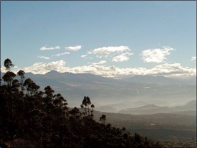 El Mojanda se ve aqu� parcialmente cubierto, al fondo a la derecha el volc�n Cus�n. Esta fotograf�a fue obtenida en la madrugada casi contra el sol, el bosque en primer plano es parte del parque Metropolitano.
