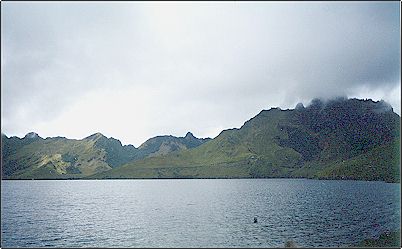 Vista de la laguna desde la orilla y las paredes de la caldera al fondo semicubiertas de vegetaci�n de p�ramo, desafortunadamente un refugio bastante grande est� en deplorable estado de destrucci�n e incendiado a conciencia, si se desea acampar se necesita llevar carpas y tener cuidado con el fuego para no causar incendios forestales.
