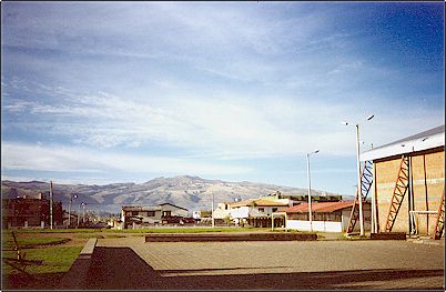 Hacia el fondo el volc�n Pambamarca tomado desde la ciudad de Cayambe, extinto desde hace mucho tiempo, se encuentra cubierto de cangagua, un material de distinta procedencia pero principalmente formado por cenizas de otros volcanes. Diversas grietas y quebradas se han formado  en sus faldas.
